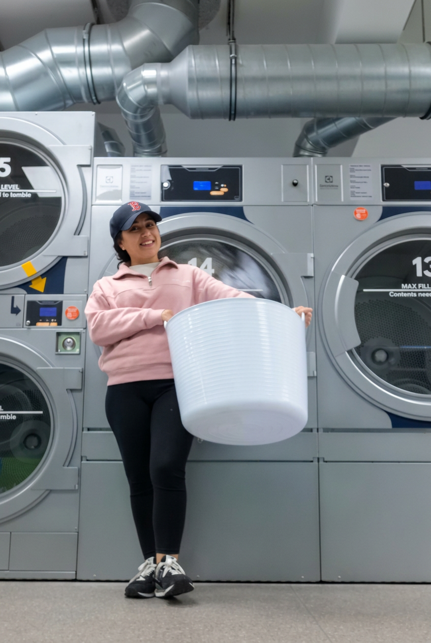 Sade holding a laundry basket at the laundromat